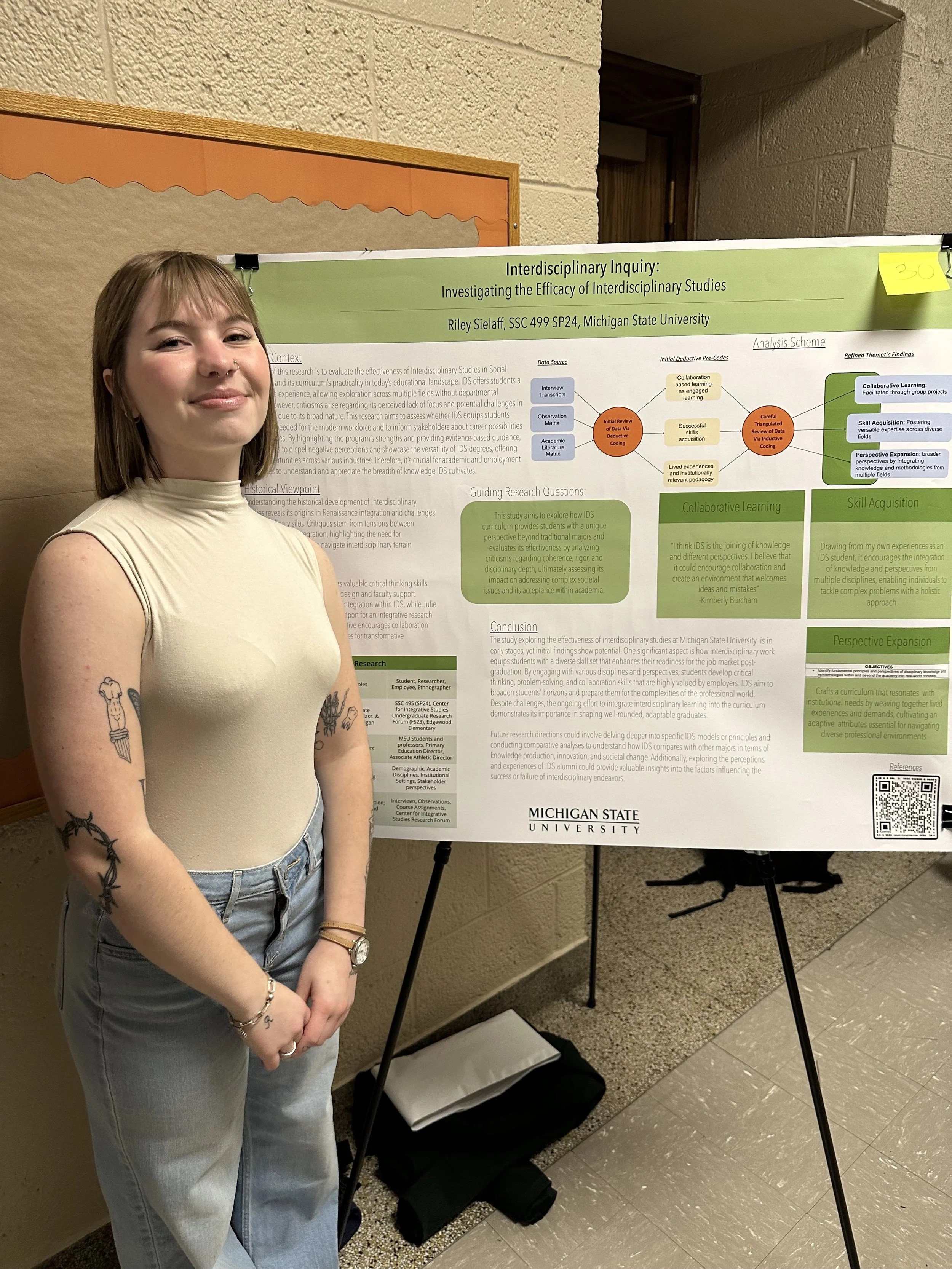 Photo of student standing in front of research poster which is one an easel. 
