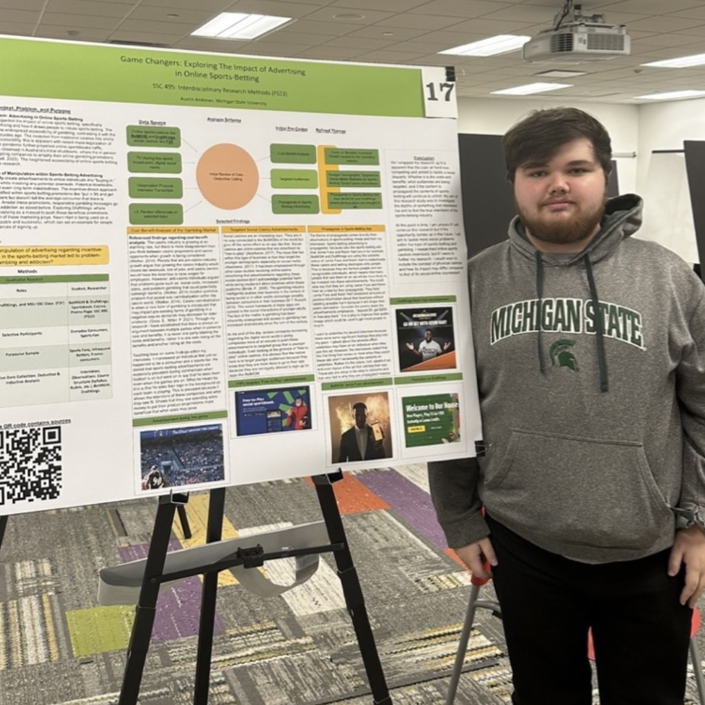 Photo of student standing in front of research poster which is one an easel. .jpg