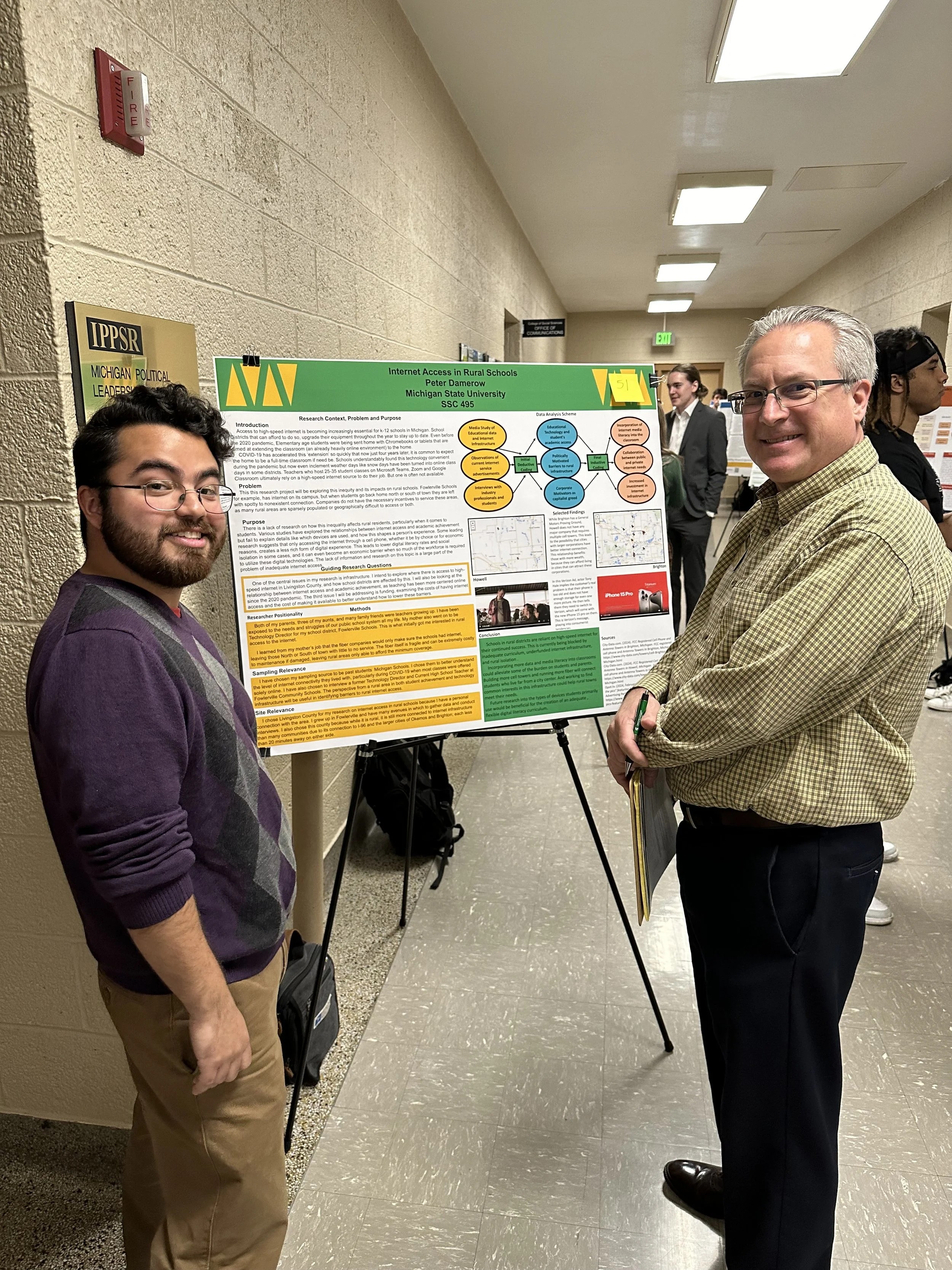 Photo of student standing in front of research poster which is one an easel. 