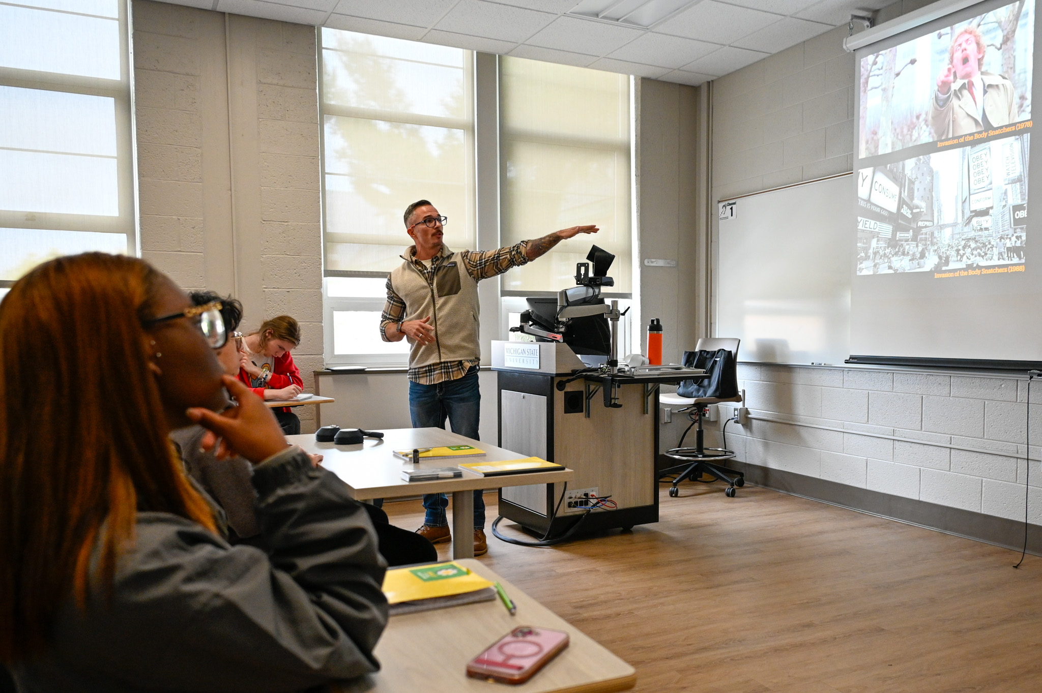 Professor David Baylis standing in front of his students and pointing at the screen.