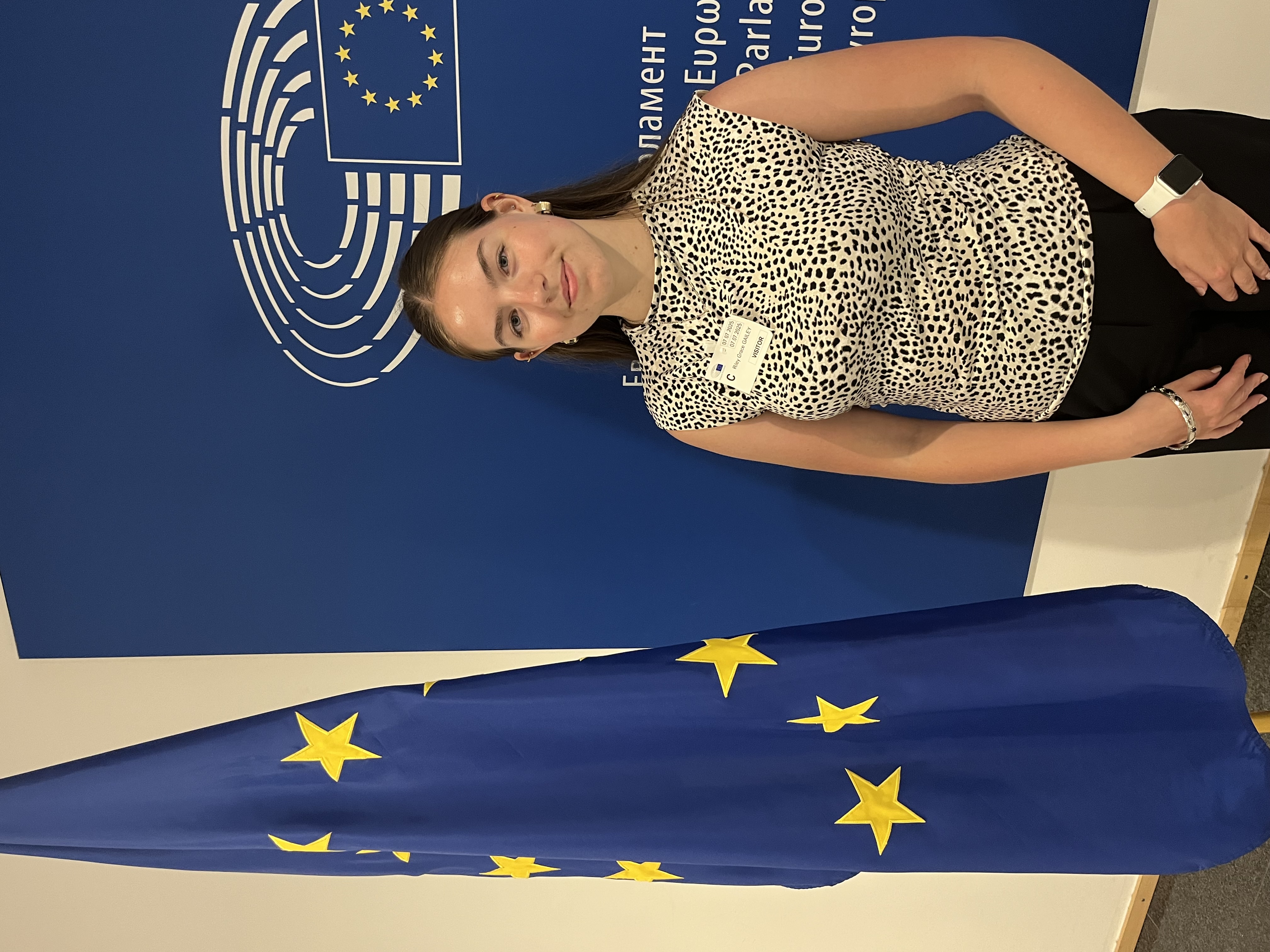 Riley Gailey standing next to a blue flag with yellow stars.